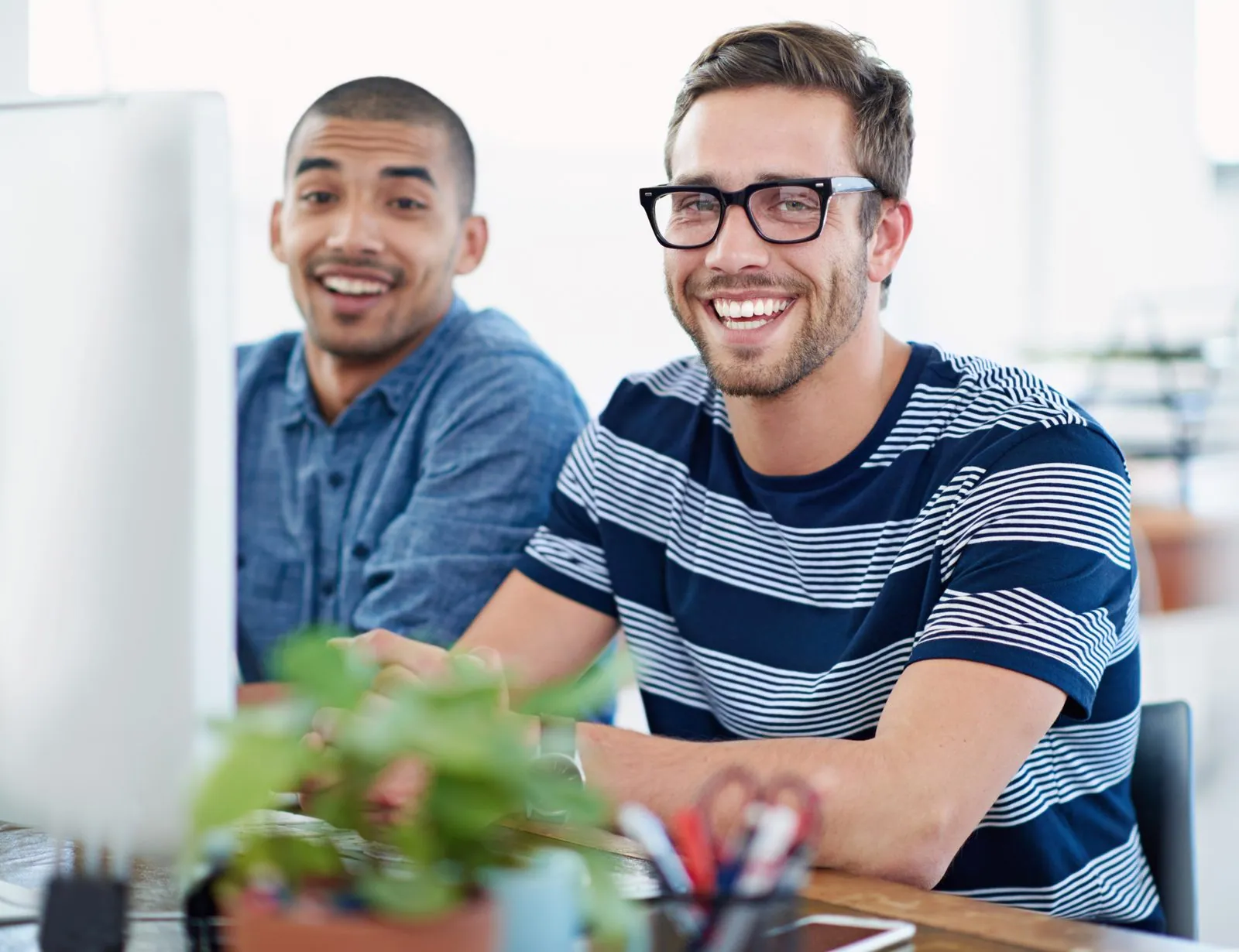 Collega’s samen achter de computer op kantoor — contact met CloudDock, IT-partner op de Veluwe